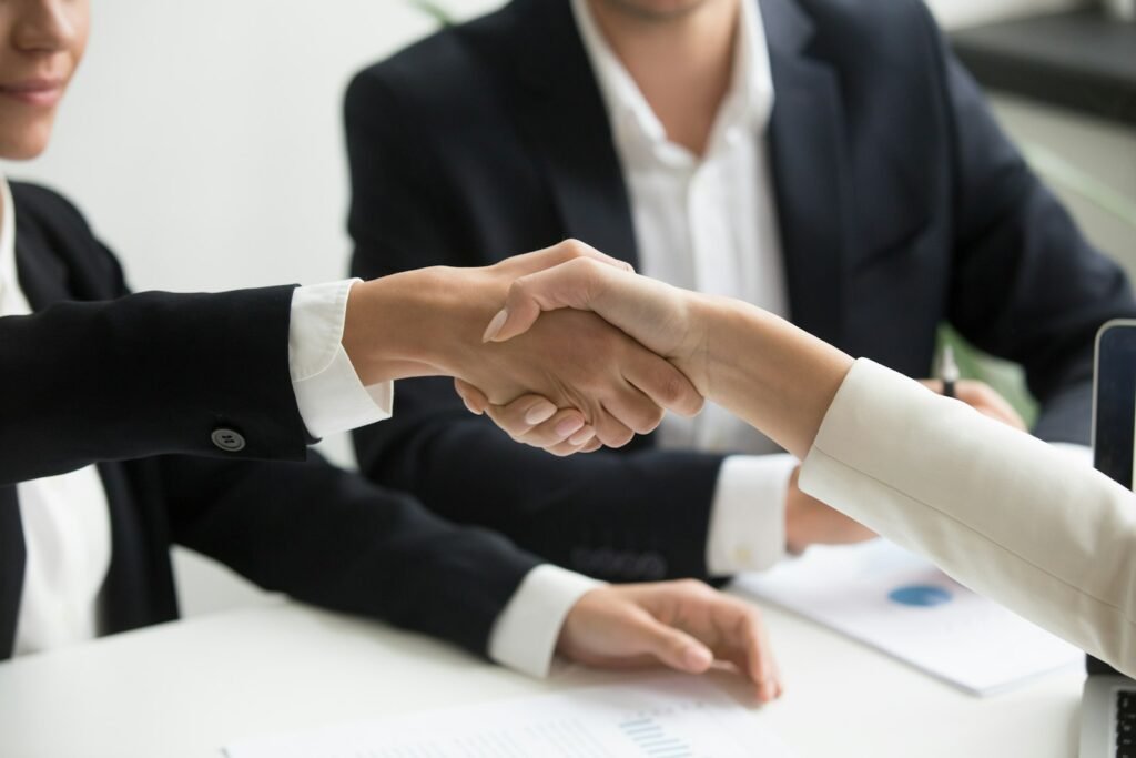 Agente inmobiliario y cliente dándose la mano al acordar la comisión